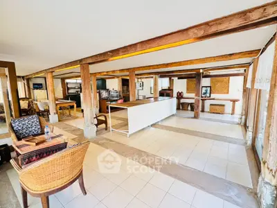 Spacious open-plan living area with rustic wooden beams and modern furnishings.
