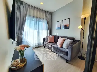 Modern living room with cozy sofa and elegant decor, featuring large window with natural light.