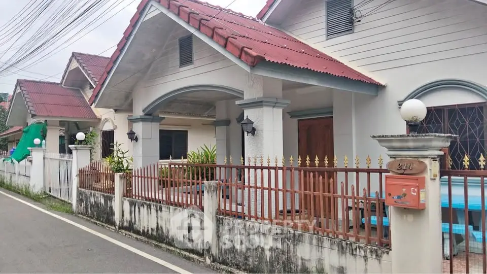 Charming suburban house with red roof and fenced front yard, perfect for family living.