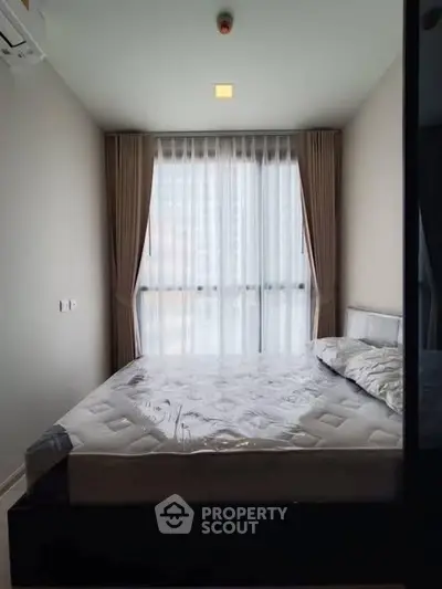 Modern bedroom with large window and elegant curtains in a stylish apartment.