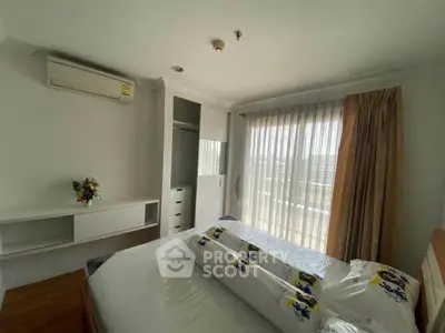 Bright bedroom with large window and modern furnishings, featuring air conditioning and ample storage space.