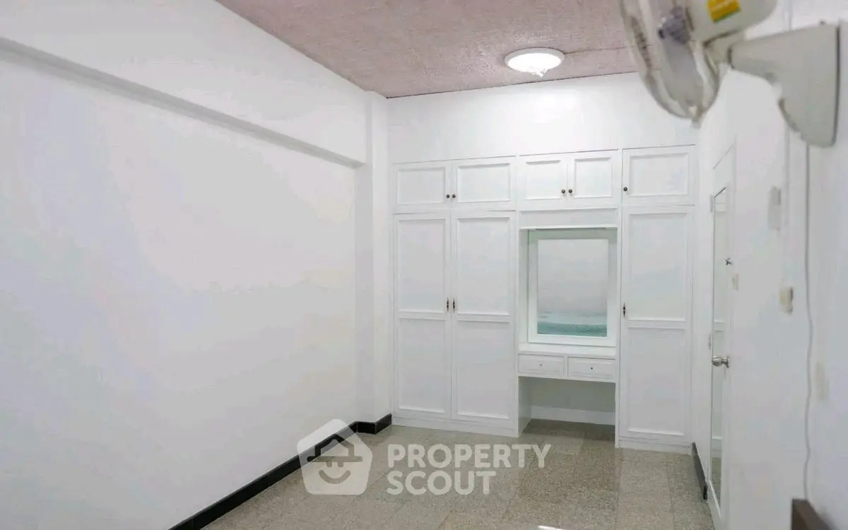 Spacious white storage room with built-in cabinets and mirror