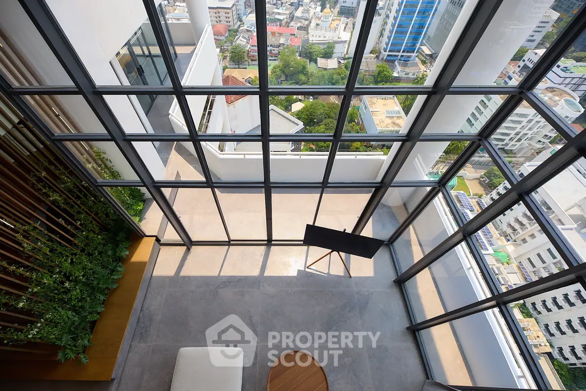 Stunning high-rise view from modern apartment with floor-to-ceiling windows and spacious balcony.