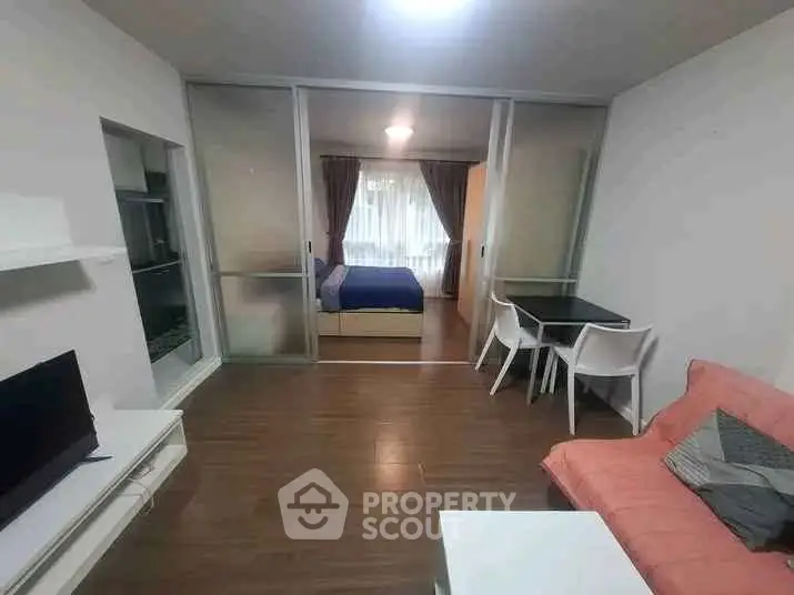 Modern studio apartment with sliding glass doors separating bedroom and living area, featuring sleek furniture.