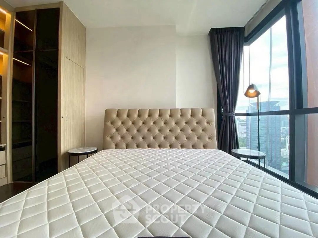 Modern bedroom with city view, featuring a plush headboard and floor-to-ceiling windows.