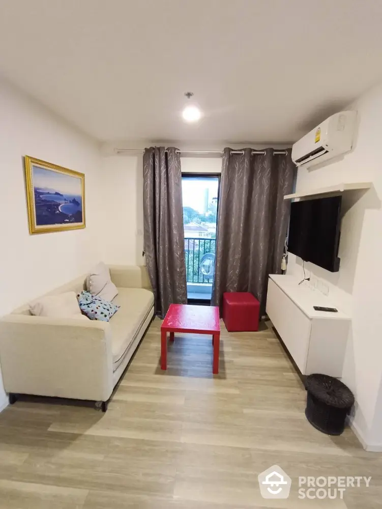 Cozy living room with modern decor, featuring a sofa, wall-mounted TV, and balcony access.