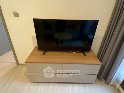 Modern living room with sleek TV on stylish wooden cabinet, perfect for cozy entertainment.