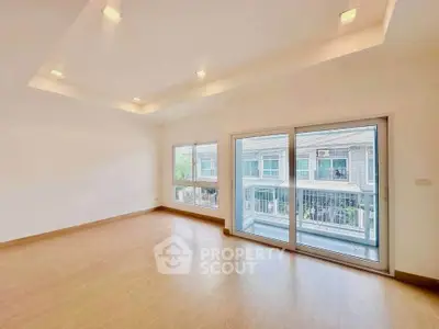 Spacious empty living room with large windows and balcony access in modern apartment.