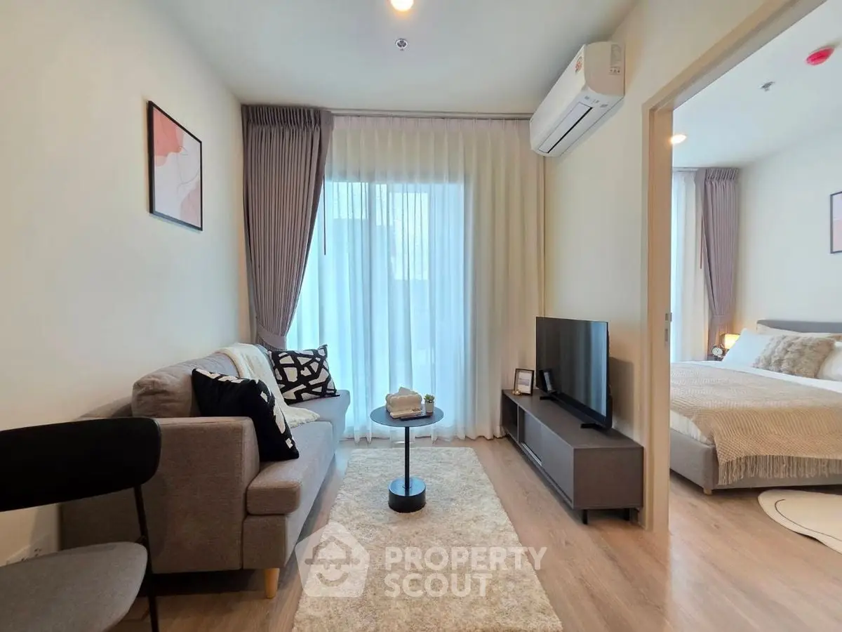 Modern living room with cozy sofa and TV, adjacent to a stylish bedroom.