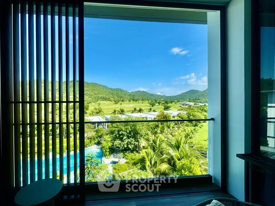 Stunning view from a modern apartment overlooking lush greenery and a serene pool.