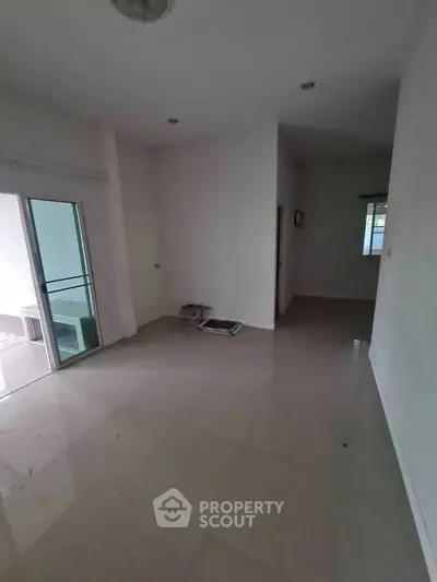 Spacious empty room with sliding glass door and tiled flooring, ideal for customization.