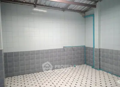 Spacious tiled room with modern plumbing, ideal for versatile use in real estate property.