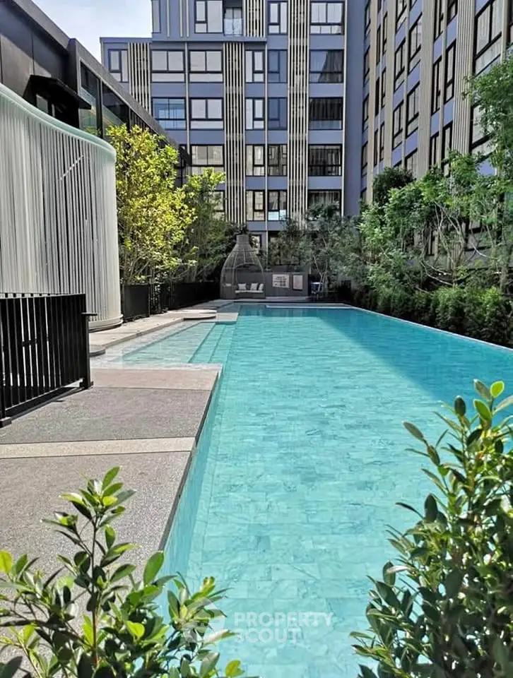 Luxurious modern apartment complex with a stunning outdoor pool and lush greenery.
