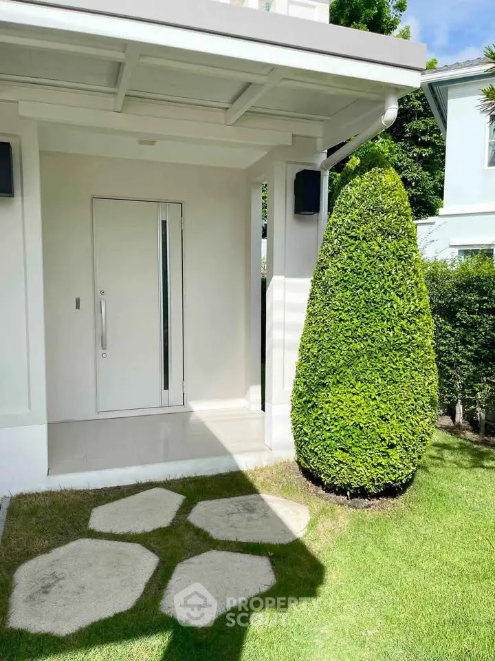 Charming modern entrance with manicured garden and sleek door design.