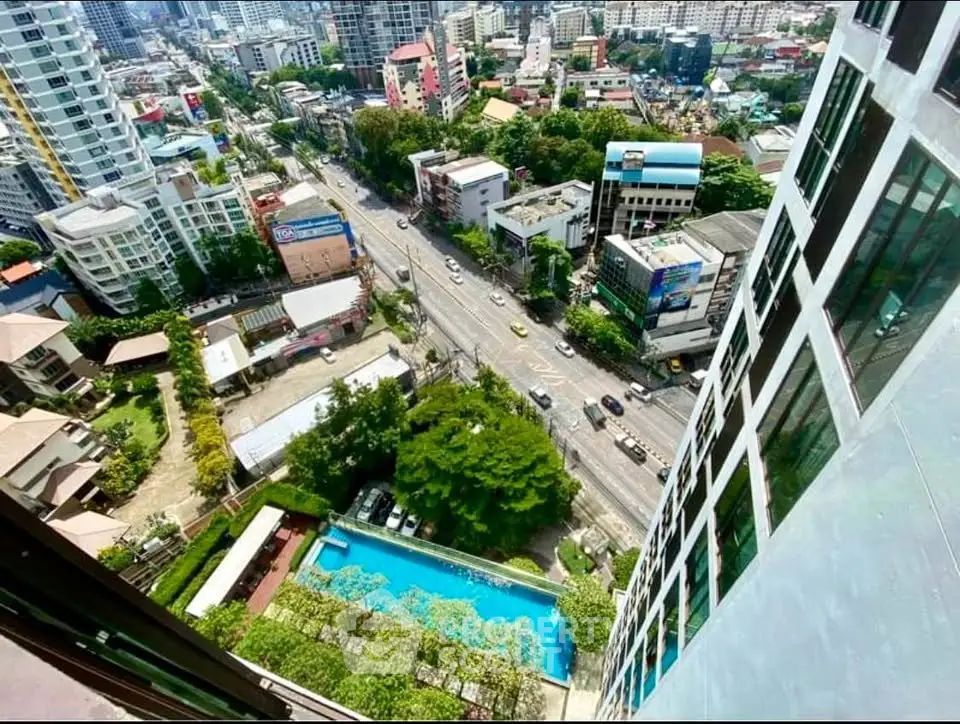 Stunning cityscape view from high-rise building with pool and lush greenery below.