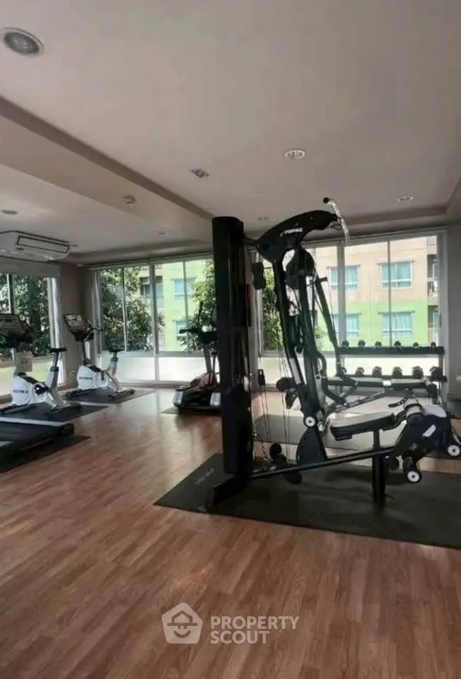 Spacious gym with modern equipment and large windows in a residential building.