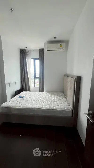 Spacious bedroom with large window and air conditioning in modern apartment.