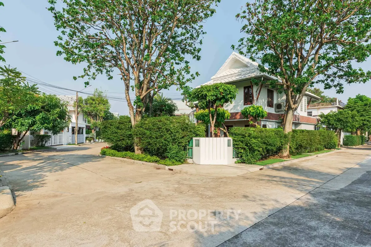 Charming suburban house with lush greenery and spacious driveway in a peaceful neighborhood.