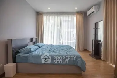 Spacious bedroom with modern decor and large window for natural light.