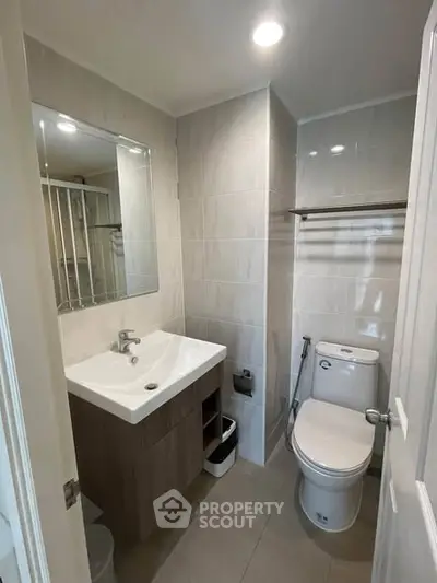 Modern bathroom with sleek fixtures and neutral tiles, featuring a spacious vanity and large mirror.