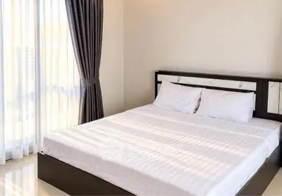 Bright and airy bedroom with large window and elegant curtains, perfect for relaxation.
