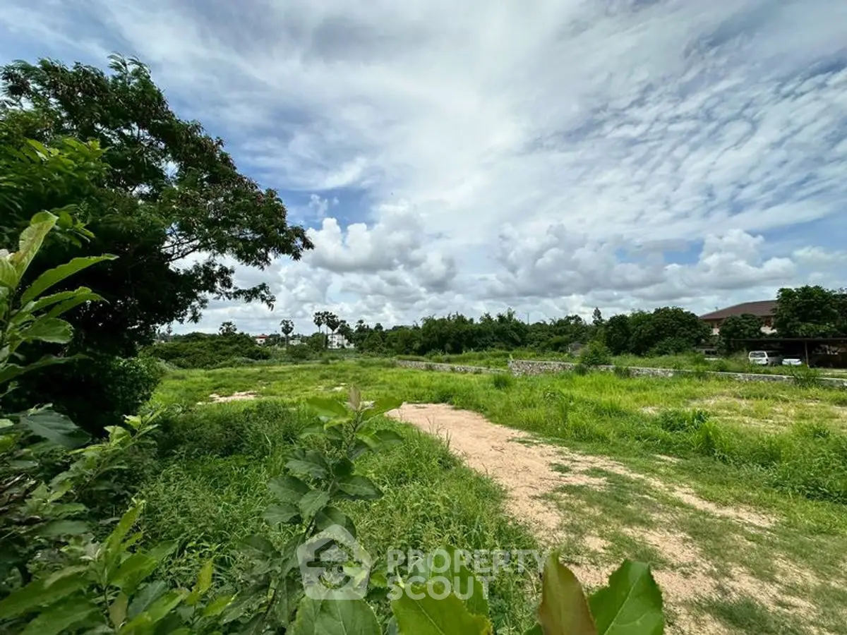 Expansive green land with lush vegetation and clear skies, perfect for development.