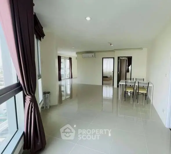 Spacious modern apartment with large windows and dining area, offering abundant natural light.