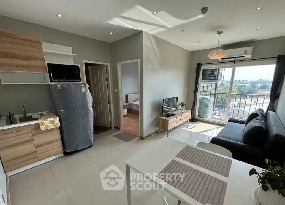Modern open-plan living room with kitchen, featuring sleek furniture and natural light.