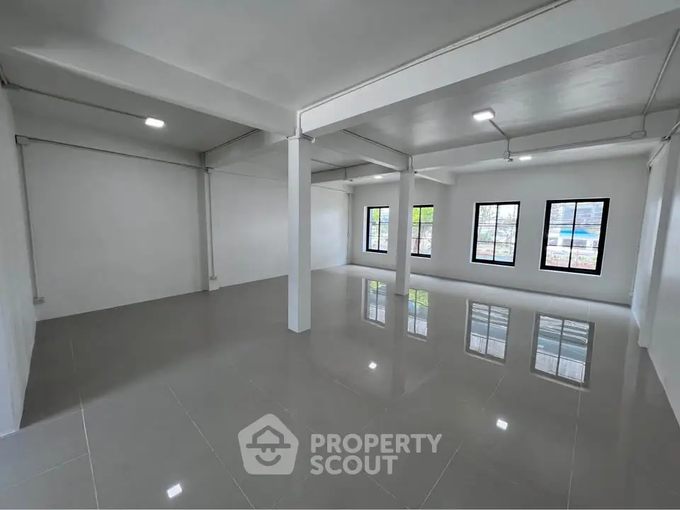 Spacious open-plan interior with large windows and glossy tiled floors, ideal for versatile living or office space.