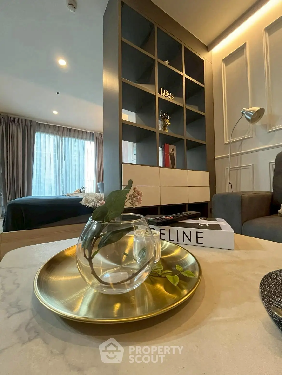 Modern living room with stylish decor and open layout, featuring a cozy seating area and elegant shelving.