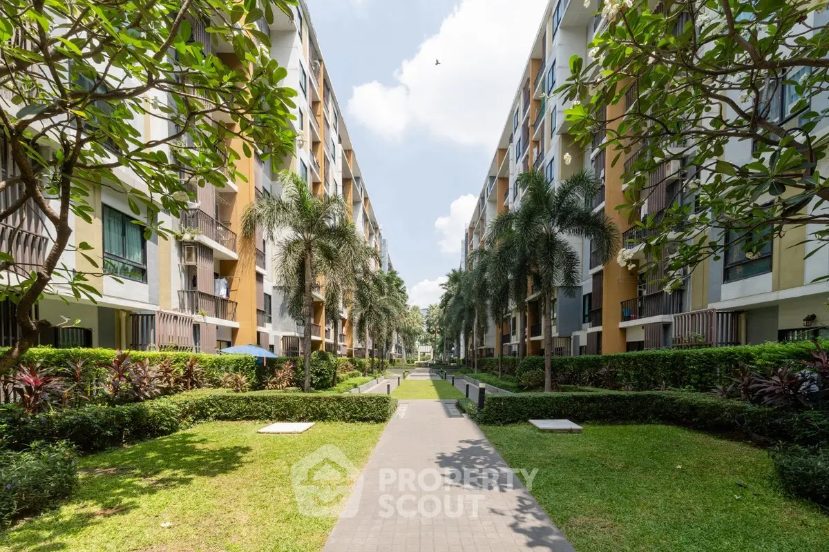Beautiful garden view of modern apartment complex with lush greenery and palm trees.