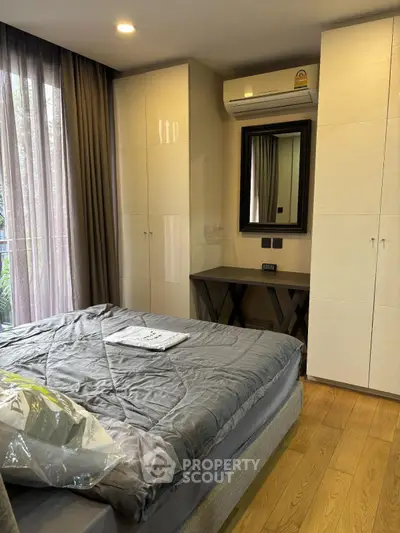 Modern bedroom with stylish decor, featuring a cozy bed, wooden flooring, and ample natural light from large windows.