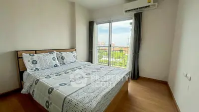 Bright bedroom with balcony and city view, featuring modern decor and air conditioning.