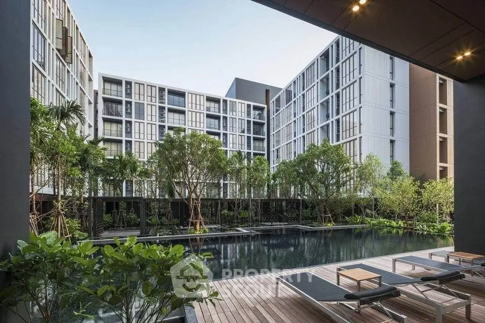 Luxurious modern apartment complex with serene pool and lush greenery, offering a tranquil urban oasis.