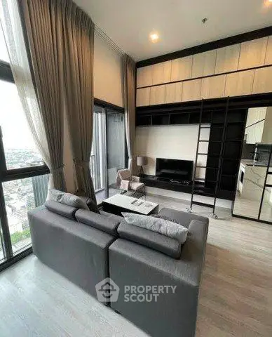 Modern living room with high ceilings and large windows offering city views.