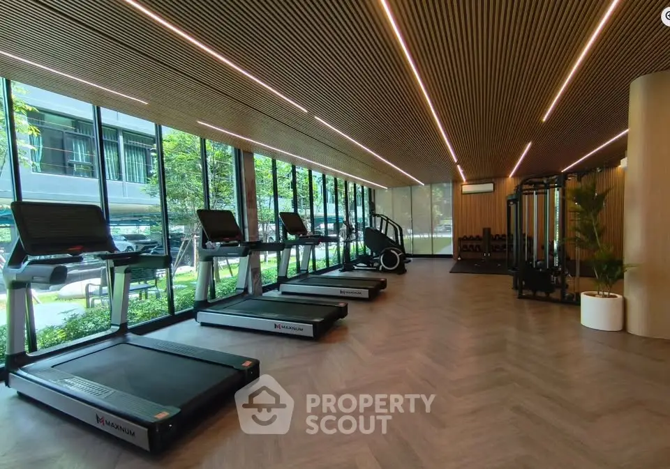 Modern gym with treadmills and large windows overlooking garden