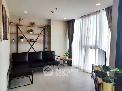 Modern living room with sleek black sofa, large window, and stylish shelving unit.