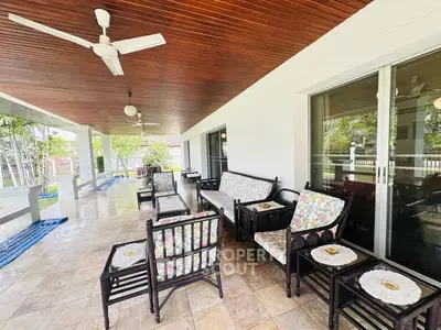 Spacious covered patio with elegant seating and ceiling fans, perfect for outdoor relaxation.