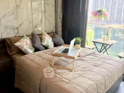 Luxurious bedroom with balcony view, modern decor, and cozy workspace in a high-rise apartment.