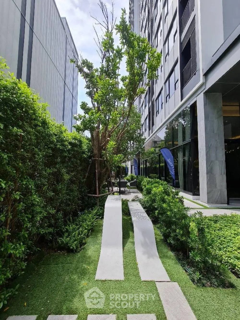 Modern building exterior with lush garden and pathway, perfect for urban living.