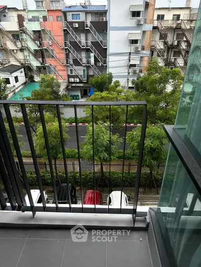 Charming balcony view overlooking a vibrant urban street with lush greenery and colorful buildings.