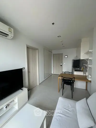 Modern living room with sleek furniture and open layout, featuring a cozy sofa and flat-screen TV.