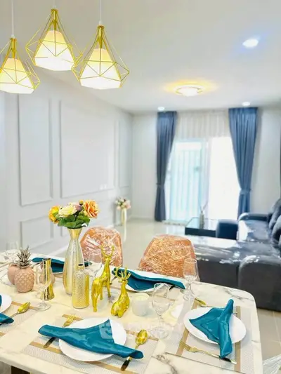Elegant living room with modern decor and stylish dining setup, featuring gold accents and plush seating.