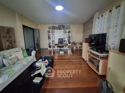 Spacious living room with wooden flooring, modern furniture, and entertainment setup.