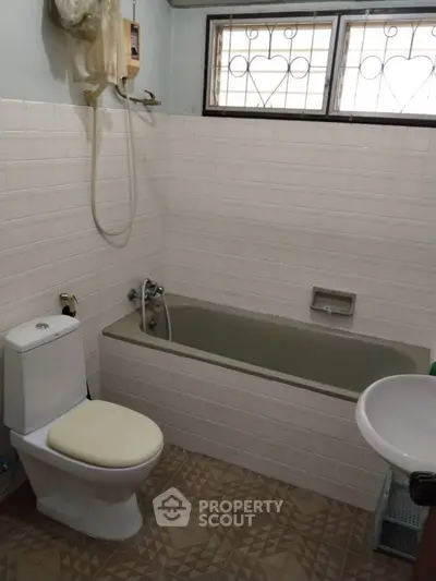 Cozy bathroom with bathtub and tiled walls, featuring a compact layout ideal for small spaces.