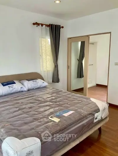 Spacious bedroom with wooden flooring and mirrored closet in modern apartment.