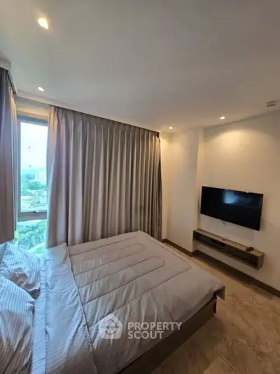 Modern bedroom with large window and wall-mounted TV, offering a cozy and inviting atmosphere.