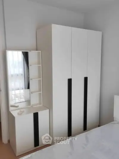 Modern bedroom with sleek white wardrobe and matching dresser, perfect for stylish storage solutions.