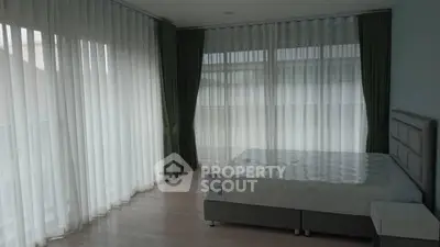 Spacious bedroom with large windows and elegant curtains in modern apartment