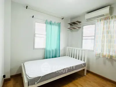 Bright bedroom with minimalist decor, featuring a single bed and air conditioning.